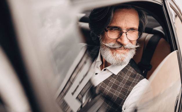Older adult male passenger smiling while seated in a MediDrive vehicle.