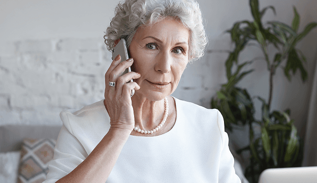 An smiling older woman talking on the phone at home.
