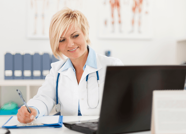 A healthcare administrator working at a laptop at a medical facility.